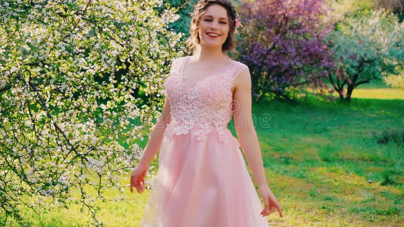 Rayons lumineux solaires. Jeune femme heureuse marche dans la nature de printemps jardin visage souriant. Joyeuse fille drôle et j clips vidéos