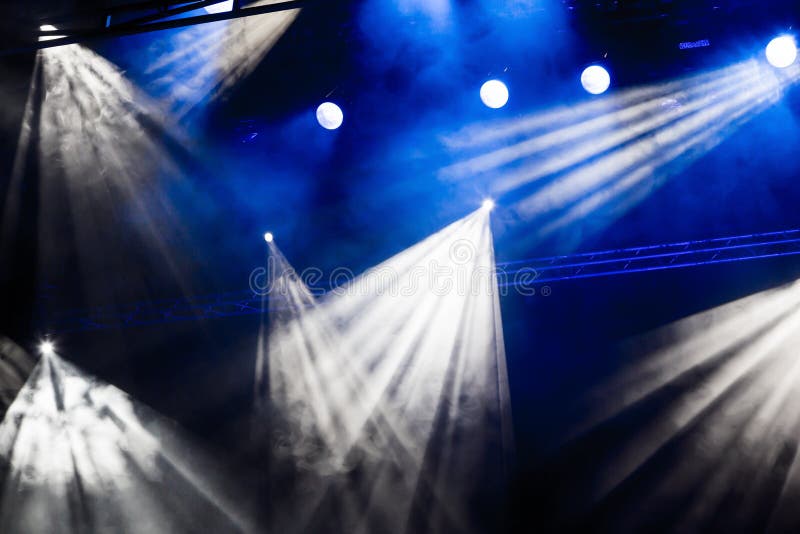 Rayos ligeros blancos y azules del proyector a través del humo en el teatro o la sala de conciertos Reflector del pasillo de la i fotografía de archivo Rayos ligeros blancos y azules del proyector a través del humo en el teatro o la sala de conciertos Reflector del pasillo de la i fotografía de archivo