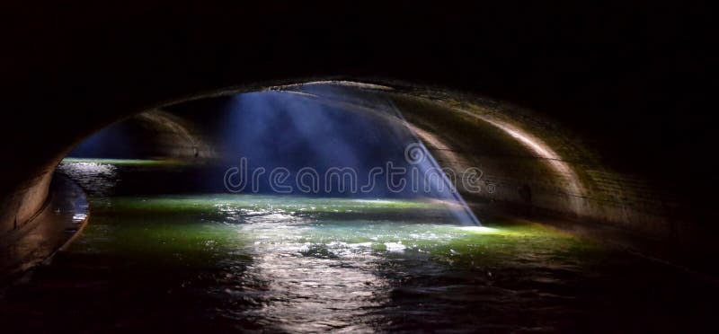 Rays of sunlight coming through a vent illuminate the waterway in an underground sector of the Canal Saint-Martin in Paris