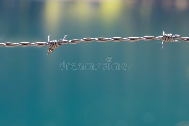 Razor barb wire sharp fence blurred background. Blurred background with macro close up of pointed sharp steel metal barbed wire as concept for prison prohibited