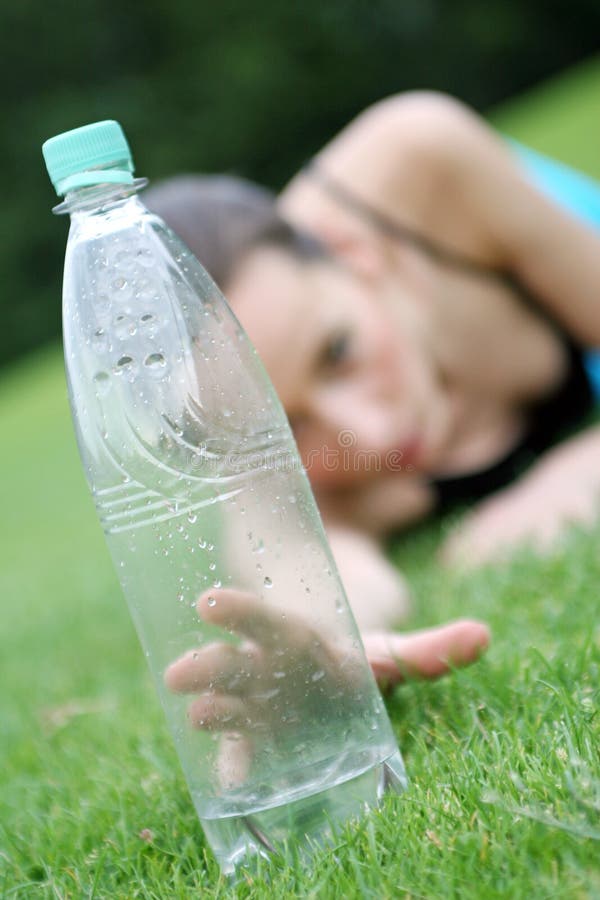 Acostada sobre el césped verde después estamos buscando sobre el beber alguno Agua.