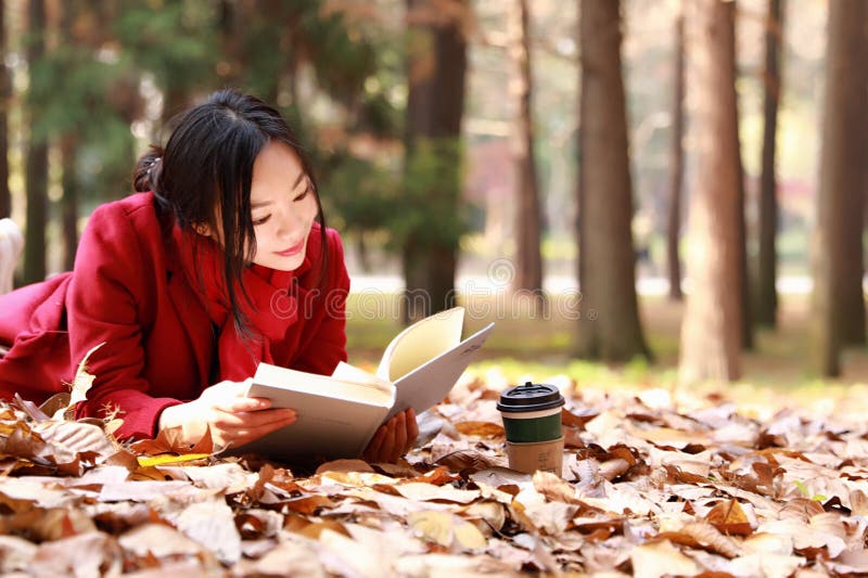 Reading in nature is my hobby,girl Read a book on the fallen leaves