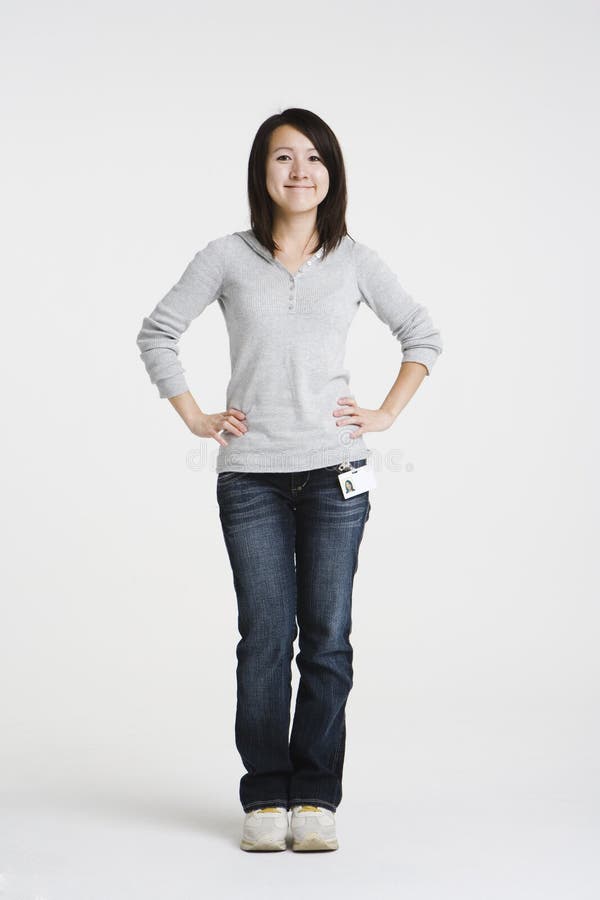 Young Asian woman wearing a employee badge has a positive attitude. She has her hands on her hips and smile. Young Asian woman wearing a employee badge has a positive attitude. She has her hands on her hips and smile.