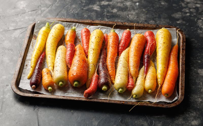 Ready To Bake Rainbow Carrots on a Parchment Lined Baking Sheet. Stock Photo Image of