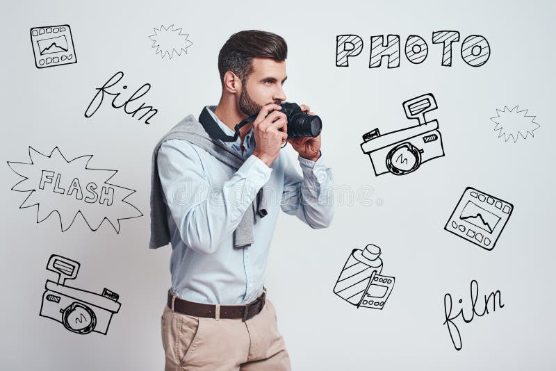 Ready to make a photo. Young attractive man is going to make a photoon digital camera while standing against grey royalty free stock images Ready to make a photo. Young attractive man is going to make a photoon digital camera while standing against grey royalty free stock images