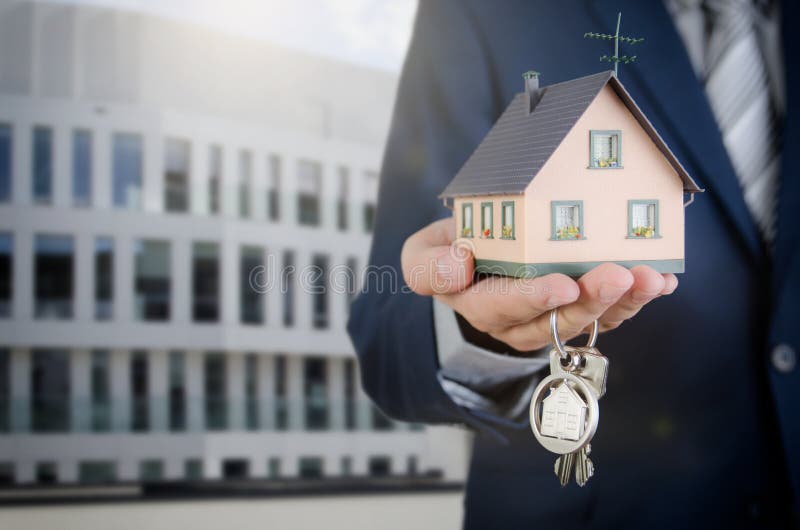 Real estate agent with home keys and house miniature