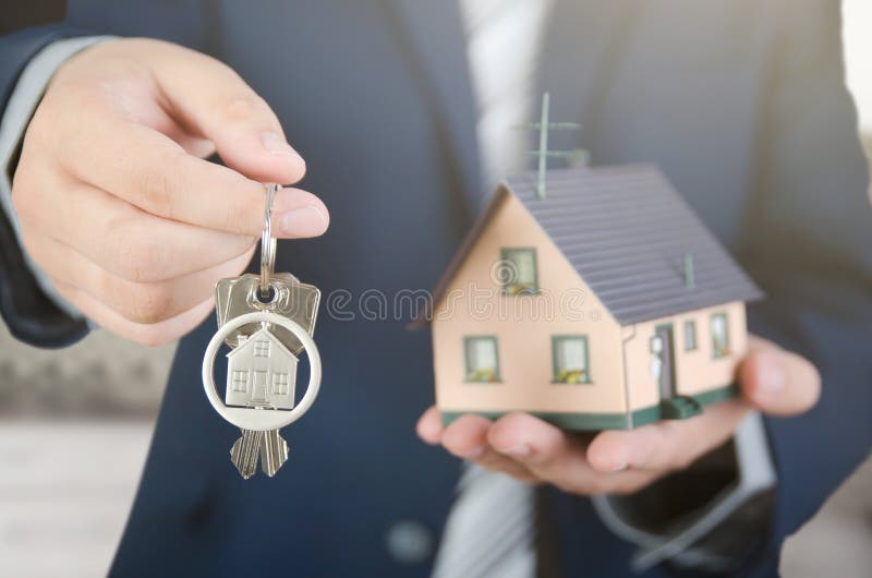 Real estate agent with home keys and house miniature