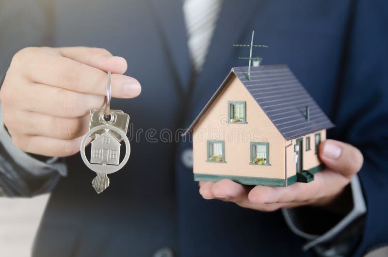 Real estate agent with home keys and house miniature