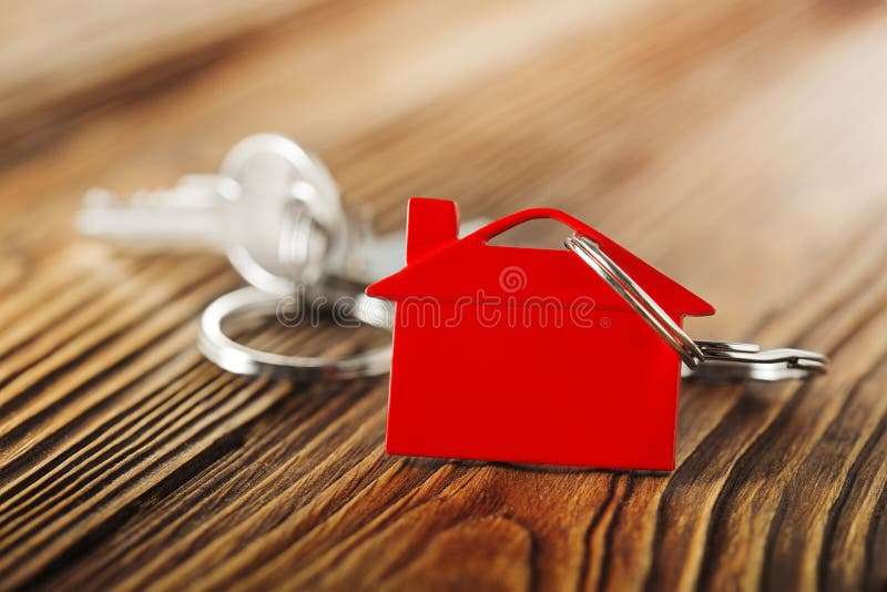 Real estate concept, red keychain with house symbol wooden backgtound