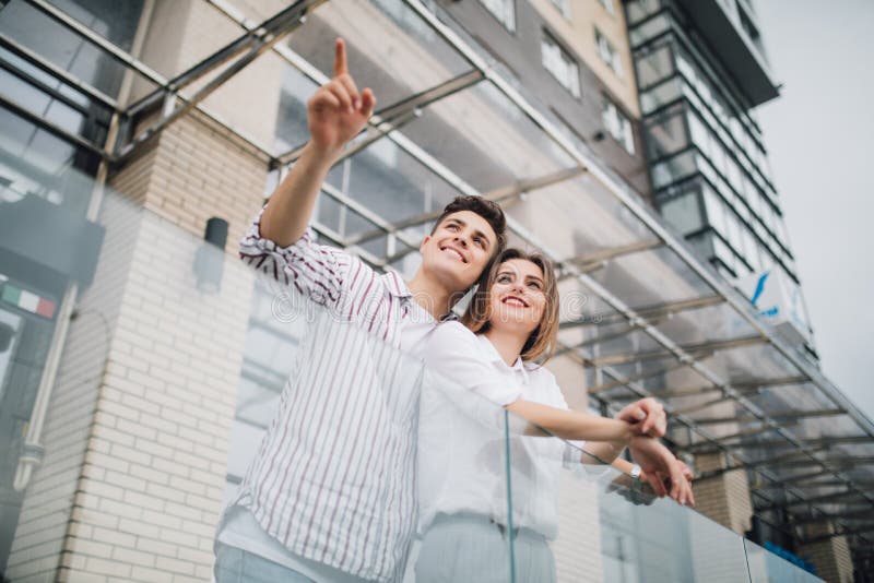 Real estate and family concept. Young couple pointed side on front of new big modern house construction stock photo Real estate and family concept. Young couple pointed side on front of new big modern house construction stock photo