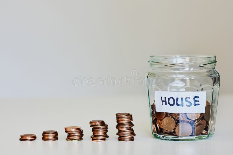 Real estate mortgage concept. Glass jar full of coins and sign house royalty free stock photo Real estate mortgage concept. Glass jar full of coins and sign house royalty free stock photo