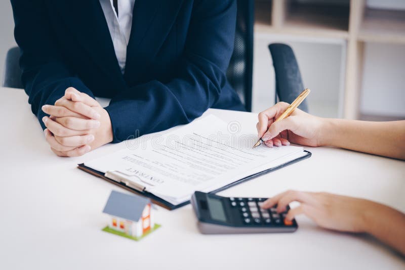Real estate services for buying home using calculator for calculating table payment to customer and pointing the pen on document s