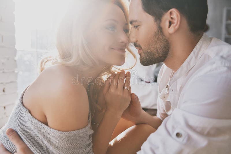 Real love. Beautiful young couple bonding and smiling while sitting in the bedroom