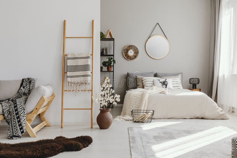 open space bedroom interior with window with curtains, mirror and clock on the wall, ladder with blanket