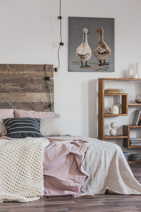 Bright, rustic bedroom interior with pink bed, wooden furniture and painting of two ducks