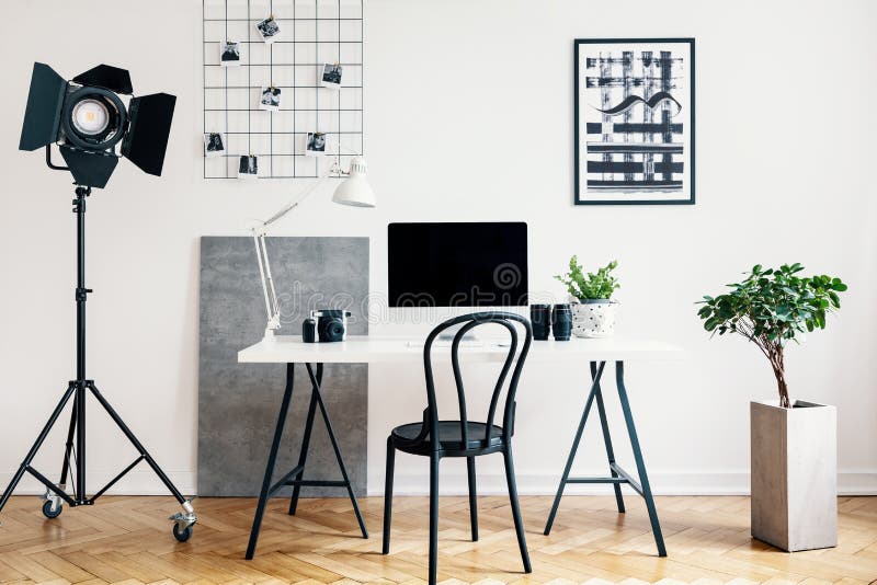 Real photo of a home office interior with a professional lamp, desk, chair, computer and plant. Place your logo on the computer screen
