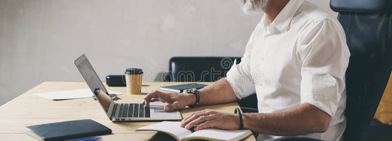 Realiteten uppsökte affärsmannen som använder den mobila bärbar datordatoren, medan sitta på trätabellen på det moderna coworking royaltyfria bilder