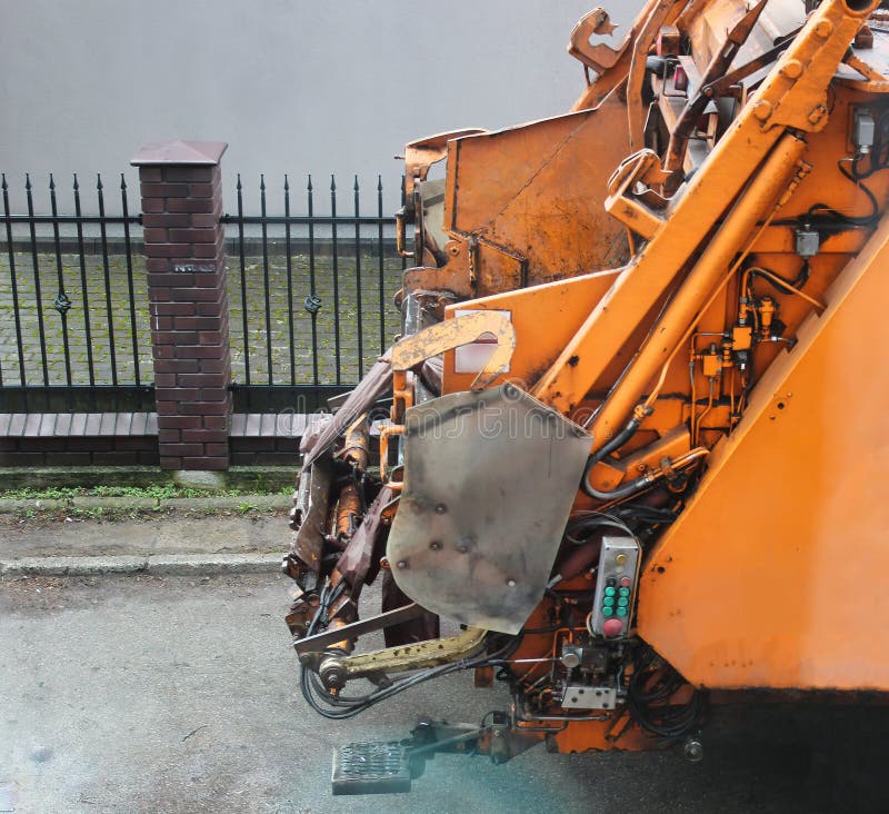 Rear End of a Typical Yellow Garbage Truck with a Crane Handle Machine