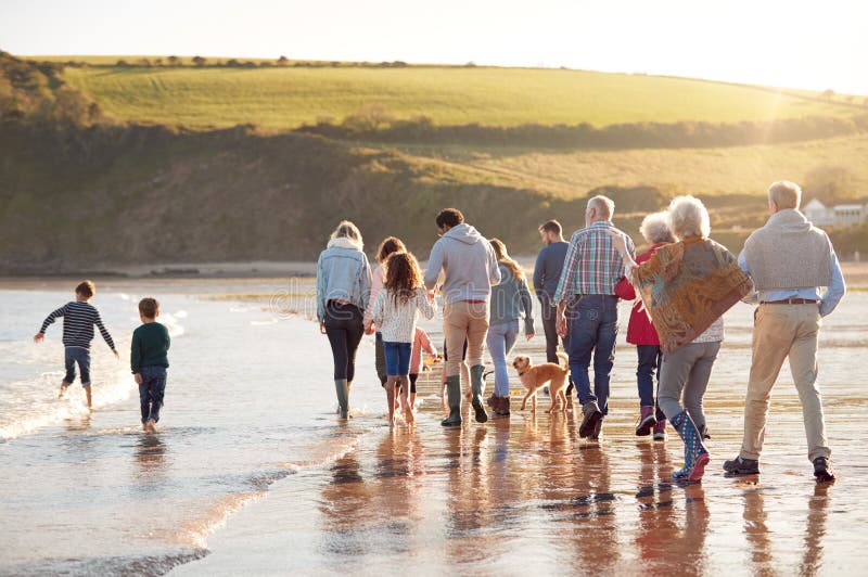 Rear View Of Active Multi-Generation Family With Dog Walking Along Shore On Winter Beach Vacation stock photos