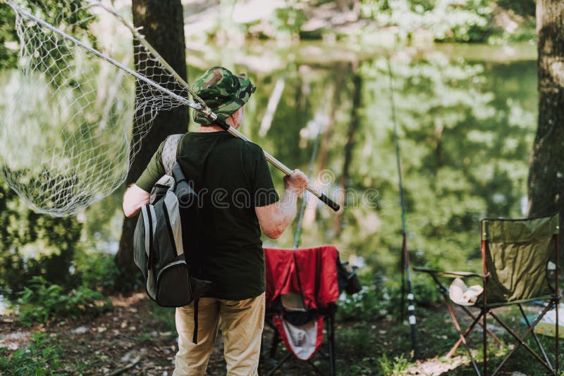 Rear view of an aged man standing with fishing equipment stock photography Rear view of an aged man standing with fishing equipment stock photography