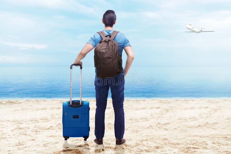 Rear view of asian man with suitcase bag and backpack standing on the beach royalty free stock photography Rear view of asian man with suitcase bag and backpack standing on the beach royalty free stock photography
