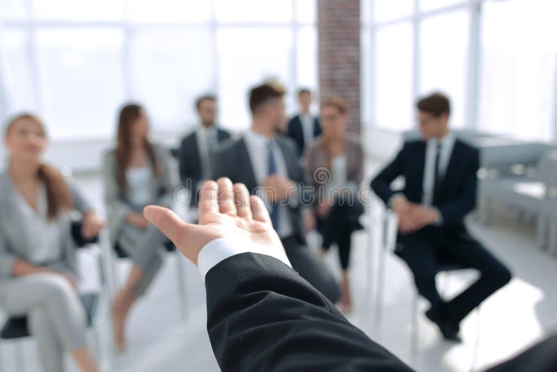 Rear view.Business coach gesturing his hand in front of a group of people.