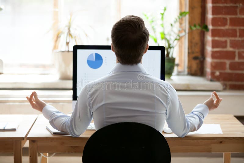 Rear view businessman sitting at desk opposite pc doing yoga royalty free stock photo
