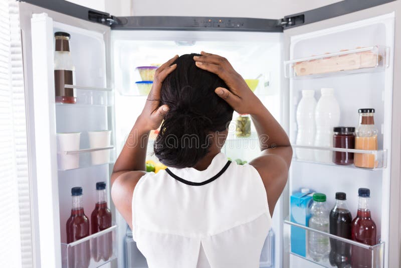 Confused Woman Looking In Open Refrigerator stock photo Confused Woman Looking In Open Refrigerator stock photo