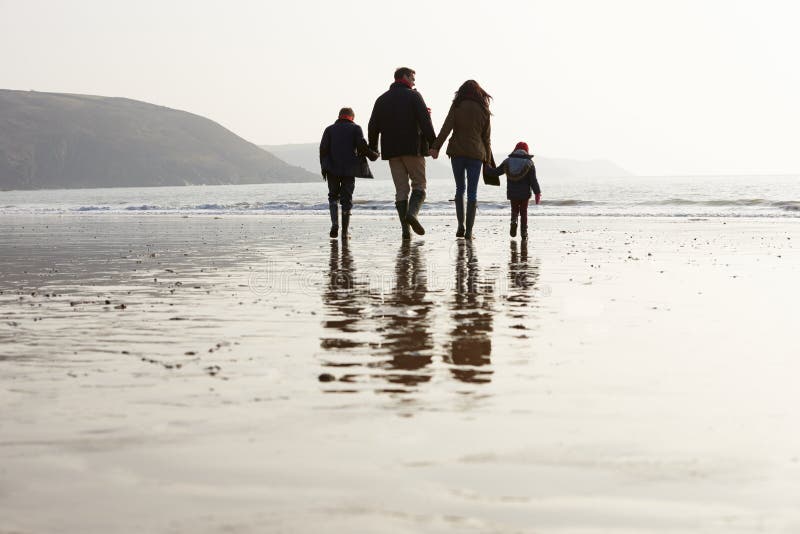 Rear View Of Family Walking Along Winter Beach