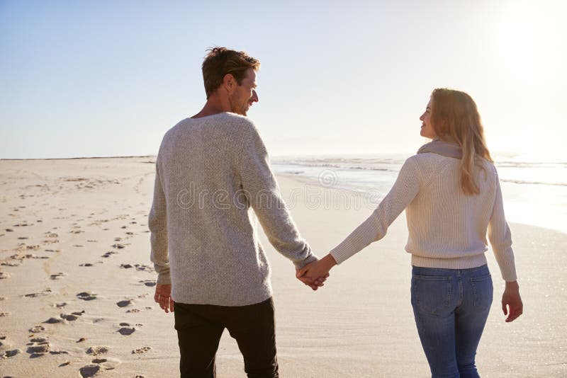 Rear View Of Loving Couple Walking Along Winter Beach Together stock images