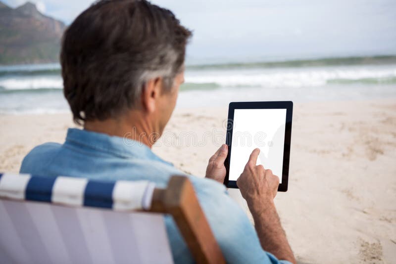 Rear view of man using digital tablet on beach