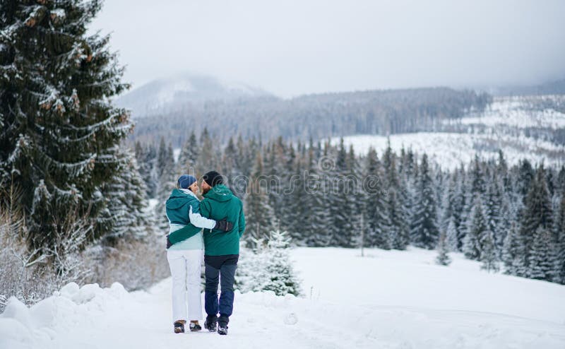 Rear view of mature couple on walk outdoors in winter nature, Tatra mountains Slovakia.