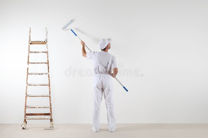 Rear view of painter man looking at blank wall, with paint stick roller and wooden ladder, on white room