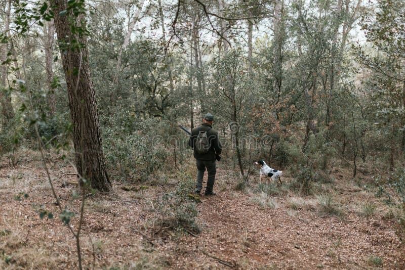 Hunter walking downhill in forest with his dog