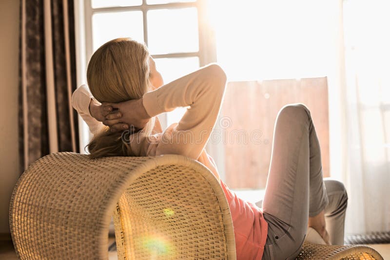 Rear view of woman relaxing on chair at home