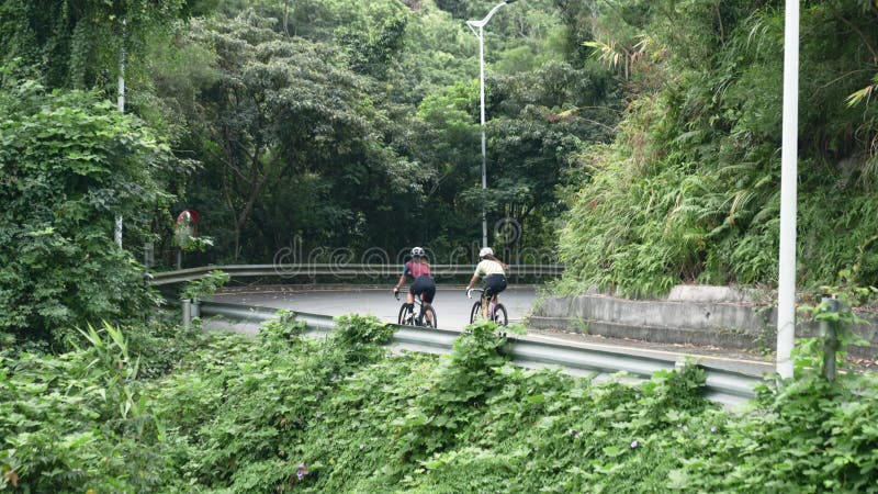 rear view of young asian cyclists riding around a curve