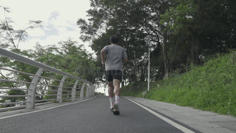 rear view of young asian man running jogging outdoors