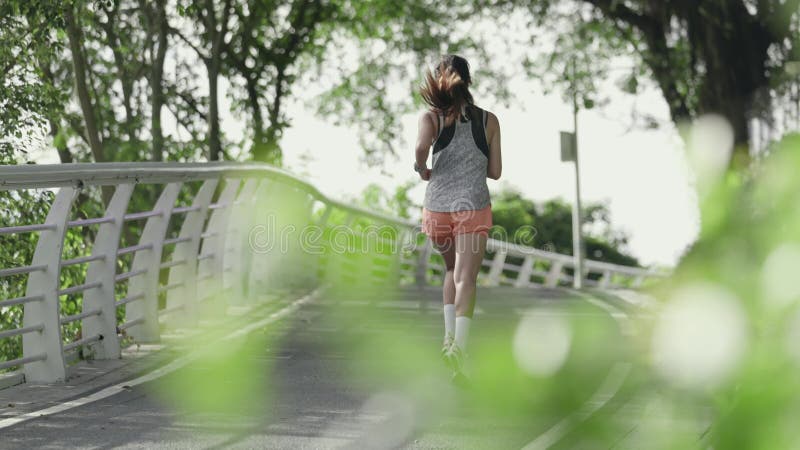 rear view of young asian woman running jogging outdoors