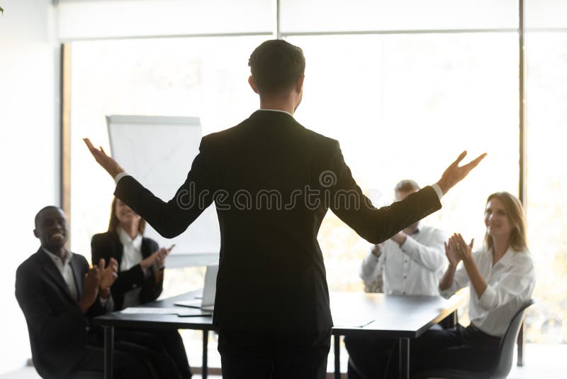 Rear view young male manager motivating business team.