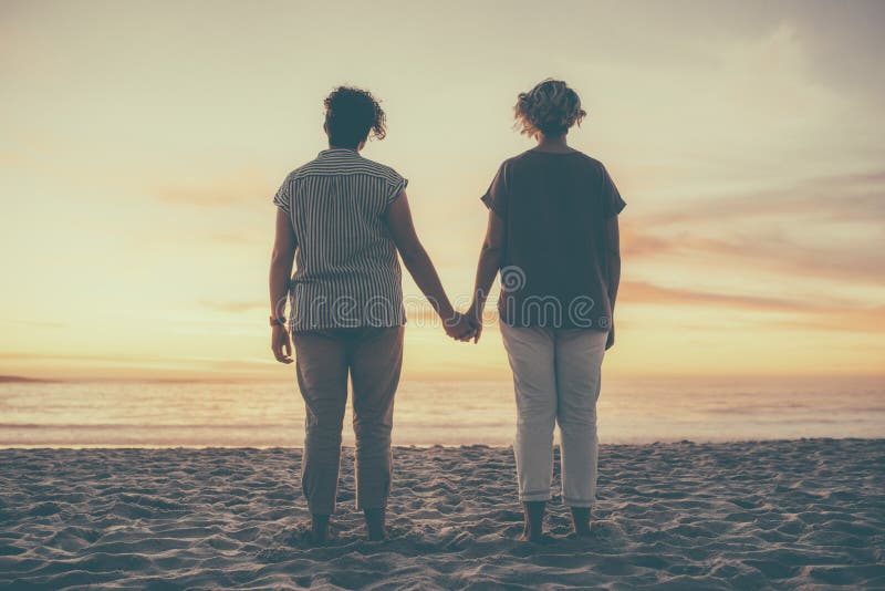 Rear view of a lesbian couple standing with holding hands stock photos