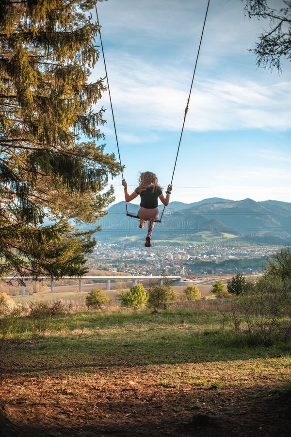 Recenze mladé ženy na houpačce na stromě na Slovensku