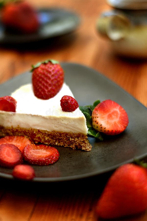 Rebanada de torta cruda de la fresa en una placa marrón fotos de archivo libres de regalías Rebanada de torta cruda de la fresa en una placa marrón fotos de archivo libres de regalías