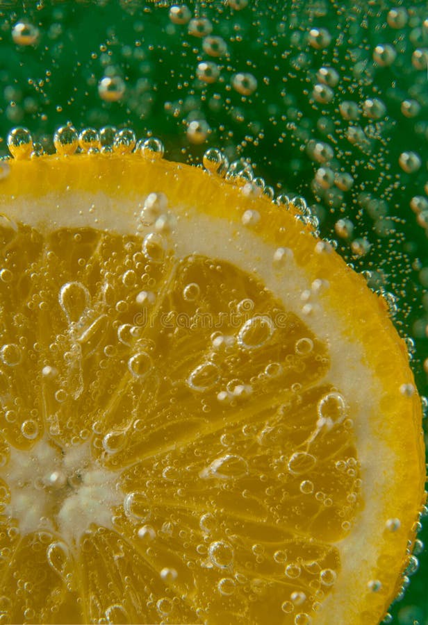 Rebanada del limón en agua con las burbujas imagen de archivo Rebanada del limón en agua con las burbujas imagen de archivo