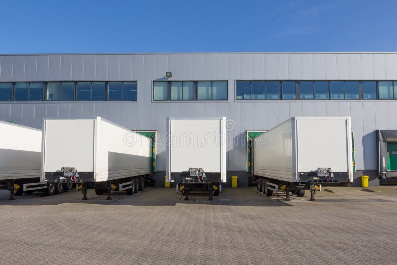 White trailers waiting to be loaded at a docking station of a distribution centre. White trailers waiting to be loaded at a docking station of a distribution centre