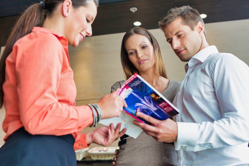 Receptionist mostra opuscolo alla coppia di imprenditori in hotel