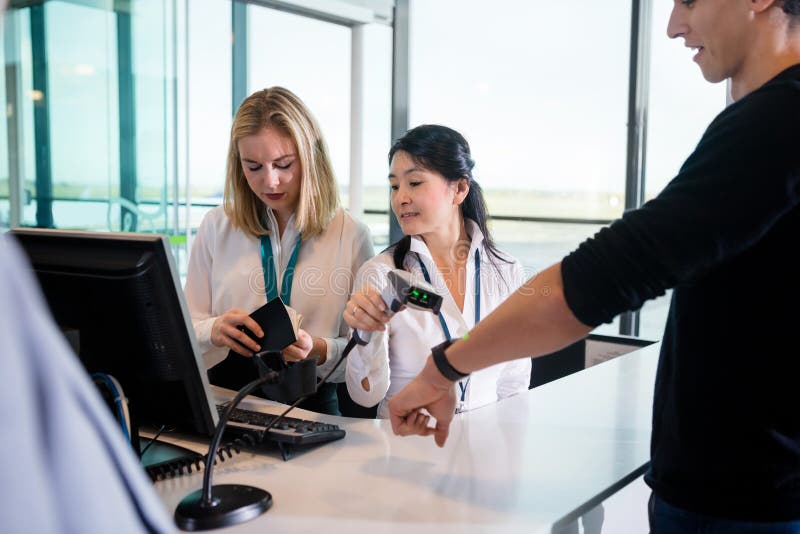 Receptionist Scanning Passengers Smart Watch While Colleague Che