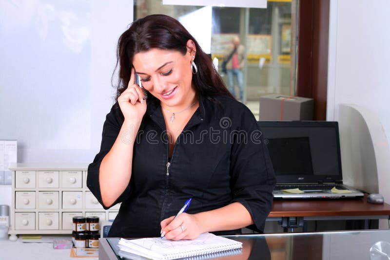 Receptionist taking note while answering a phone. Receptionist taking note while answering a phone