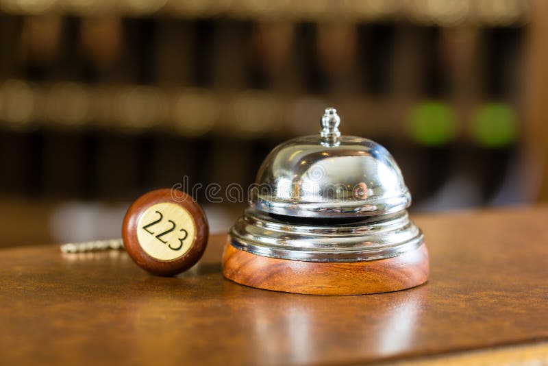 Recepção - sino e chave do hotel que encontram-se na mesa imagens de stock Recepção - sino e chave do hotel que encontram-se na mesa imagens de stock