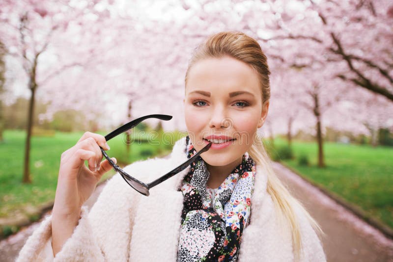 Recht junge Frau am Frühlingspark mit Sonnenbrille lizenzfreies stockfoto Recht junge Frau am Frühlingspark mit Sonnenbrille lizenzfreies stockfoto