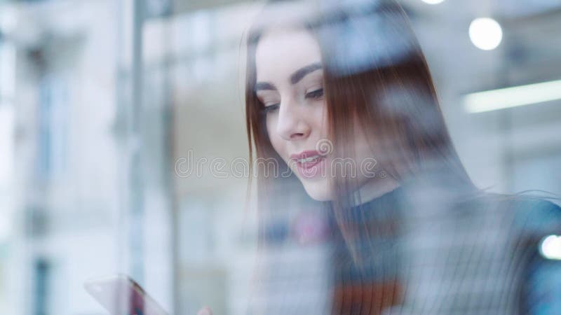 Recht junges Mädchen in einem stilvollen Blick sitzt am Fenster im café, genießt geschmackvollen heißen Kaffee, surft das Intern stock video footage Recht junges Mädchen in einem stilvollen Blick sitzt am Fenster im café, genießt geschmackvollen heißen Kaffee, surft das Intern stock video footage